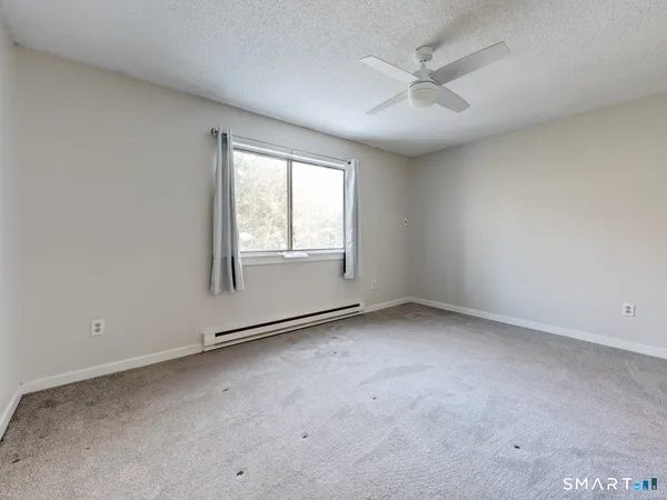 an empty room with chandelier fan and windows