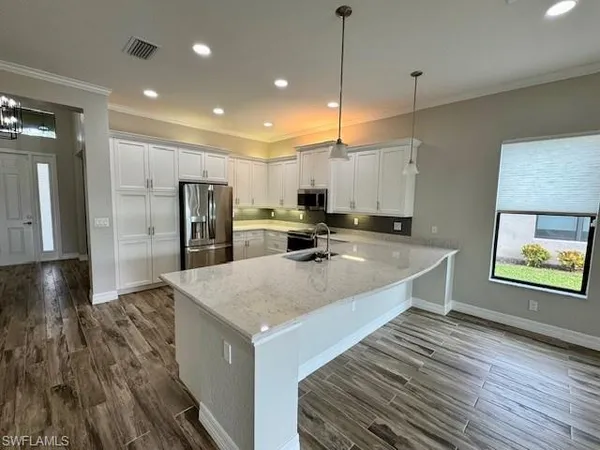 a large kitchen with kitchen island a large counter top stainless steel appliances and cabinets