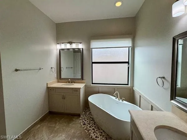 a bathroom with a tub a sink and mirror