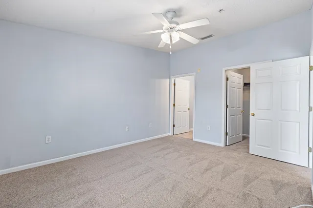 an empty room with a chandelier fan and closet area