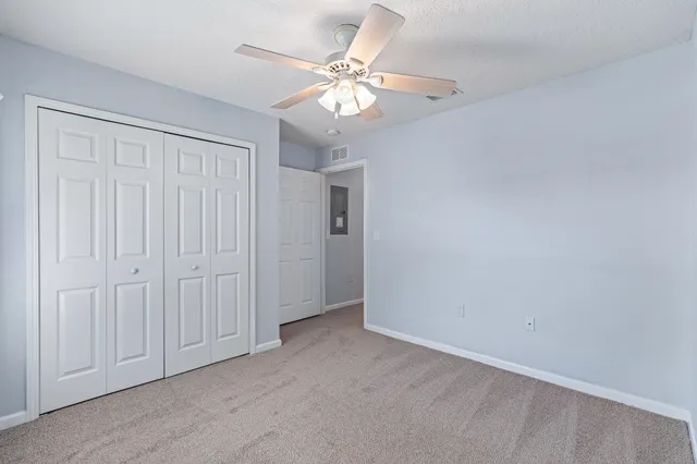 an empty room with windows and fan