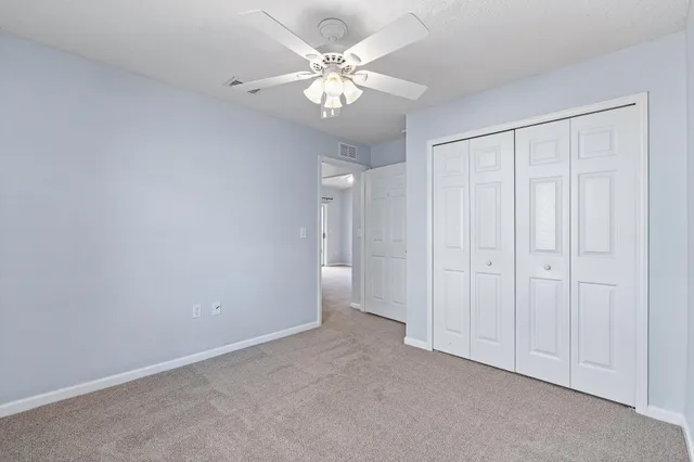 an empty room with windows and chandelier fan