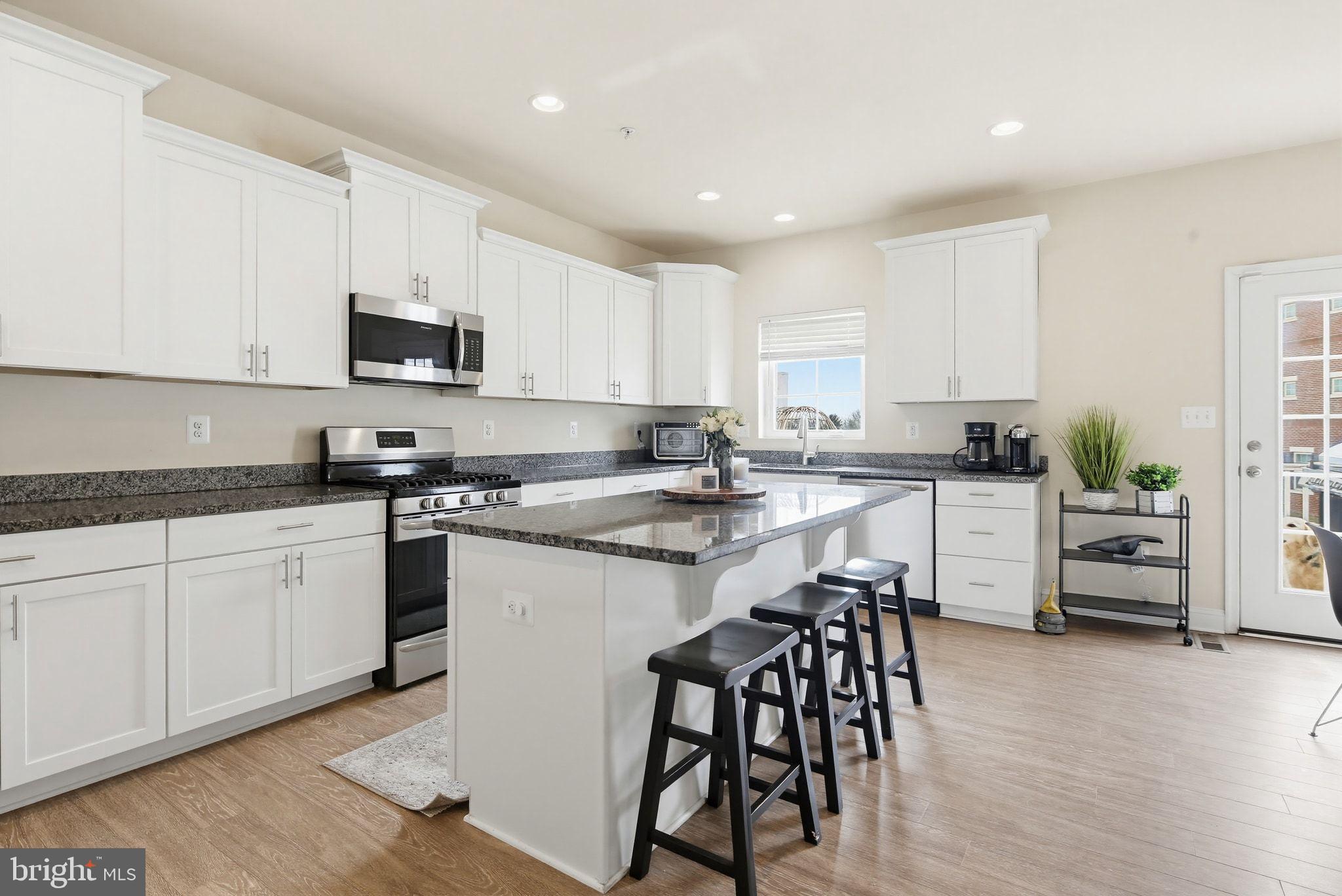5057 East Joppa Road Perry Hall, MD 21128 - Photo 3 of 29 a kitchen with stainless steel appliances granite countertop white cabinets a sink a stove a dining table and chairs