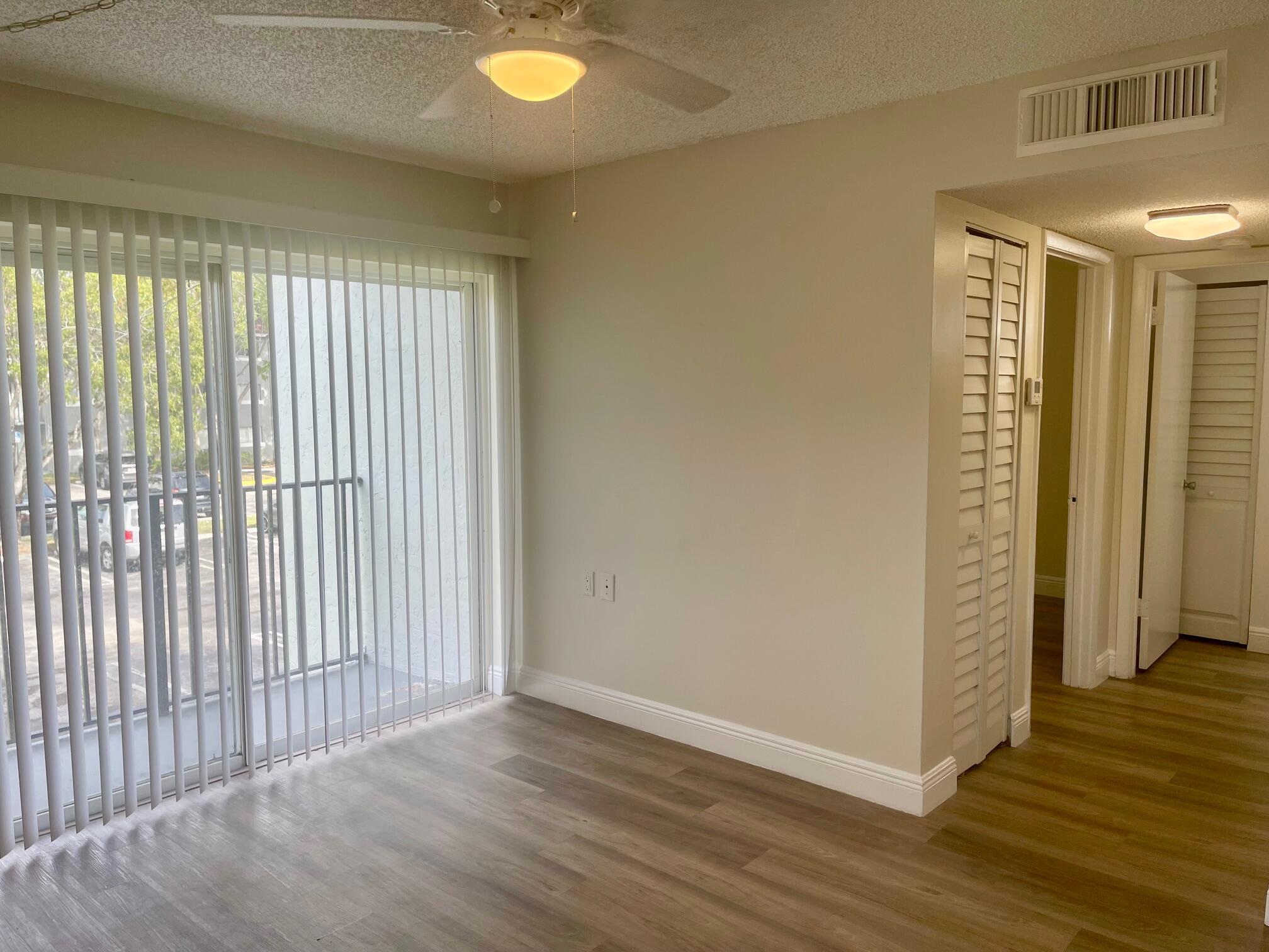 1089 Benoist Farms Road, Unit 207 West Palm Beach, FL 33411 - Photo 15 of 21 an empty room with wooden floor and windows