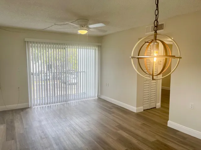 an empty room with wooden floor and chandelier