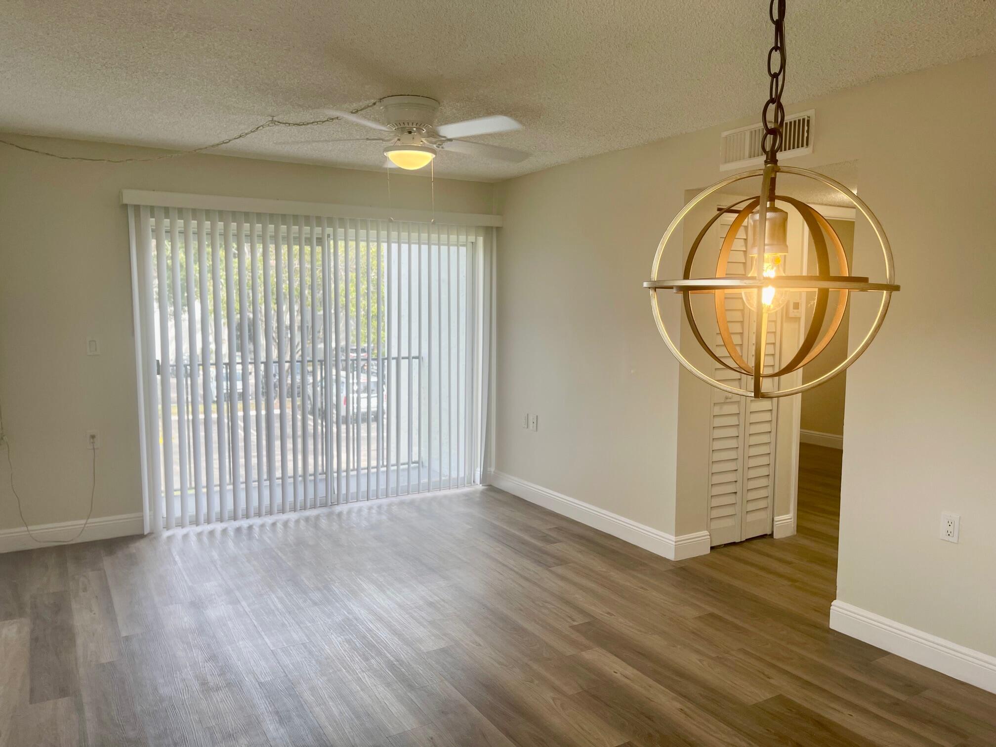 1089 Benoist Farms Road, Unit 207 West Palm Beach, FL 33411 - Photo 8 of 21 an empty room with wooden floor and chandelier