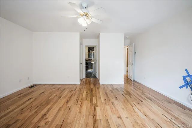 a view of empty room with wooden floor and ceiling fan