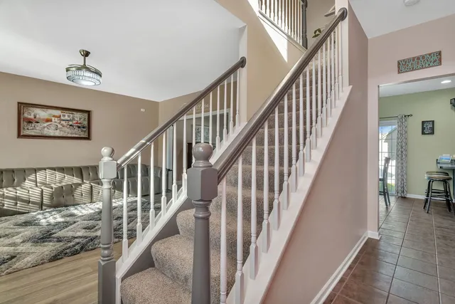 a view of staircase with lots of frames on wall and a view of a hallway