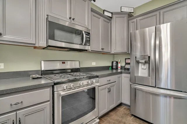 a kitchen with stainless steel appliances granite countertop a refrigerator stove and white cabinets