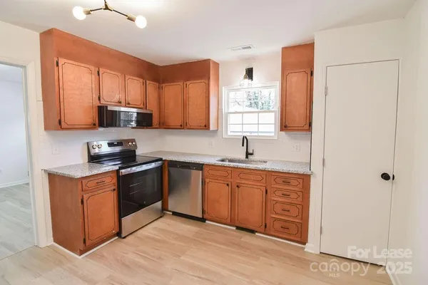 a kitchen with stainless steel appliances granite countertop a stove a sink and a refrigerator