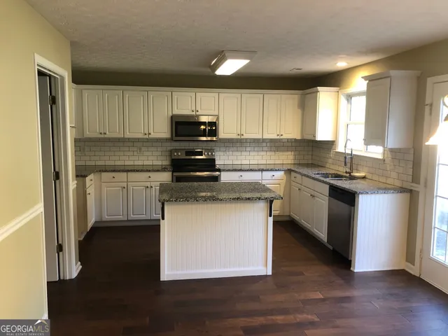 a kitchen with kitchen island granite countertop a sink cabinets and stainless steel appliances