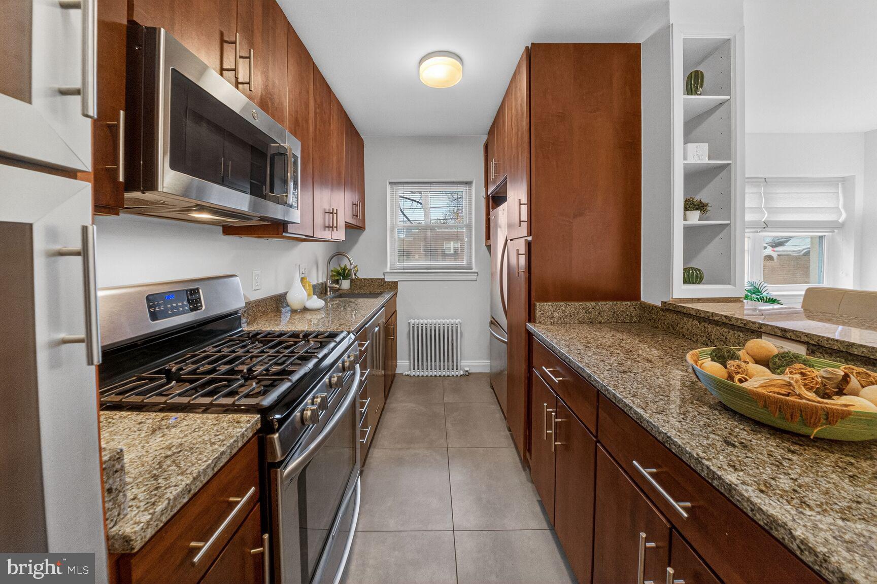 2339 40th Place Northwest, Unit 101 Washington, DC 20007 - Photo 6 of 12 a kitchen with granite countertop stainless steel appliances and wooden cabinets