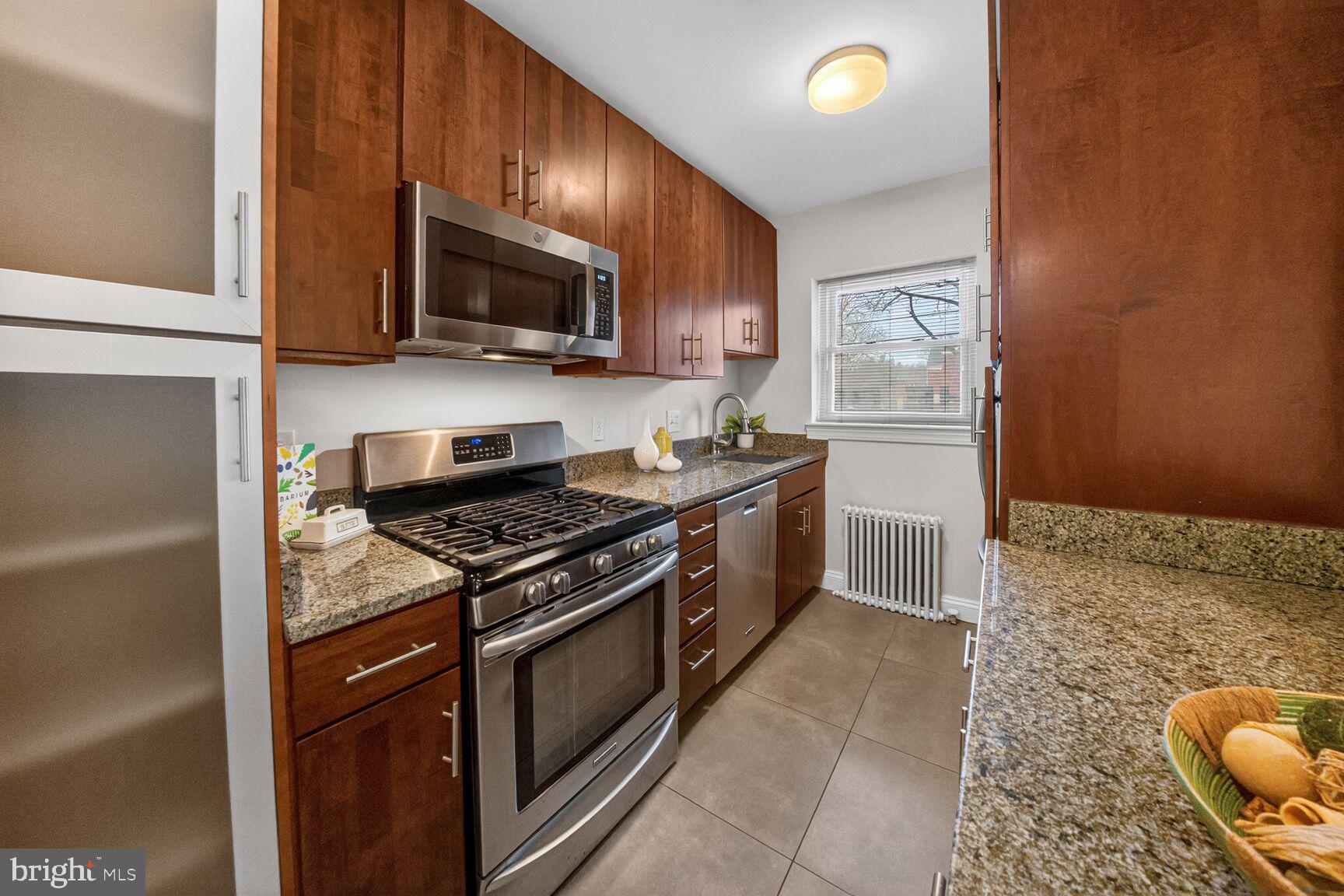 2339 40th Place Northwest, Unit 101 Washington, DC 20007 - Photo 7 of 12 a kitchen with stainless steel appliances granite countertop a stove a sink and a microwave