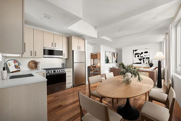 a kitchen with stainless steel appliances kitchen island granite countertop a sink dishwasher a stove a refrigerator with a dining table and chairs