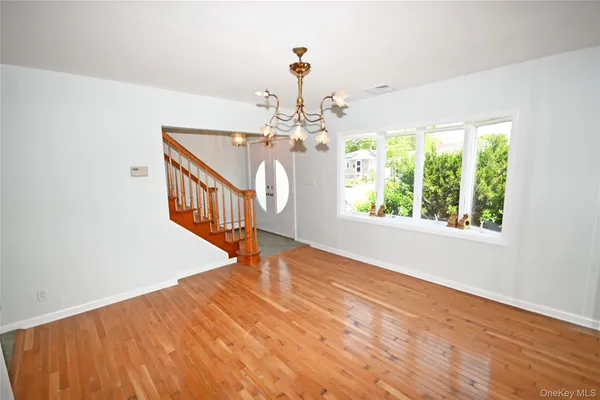 a view of a room with wooden floor staircase and a chandelier