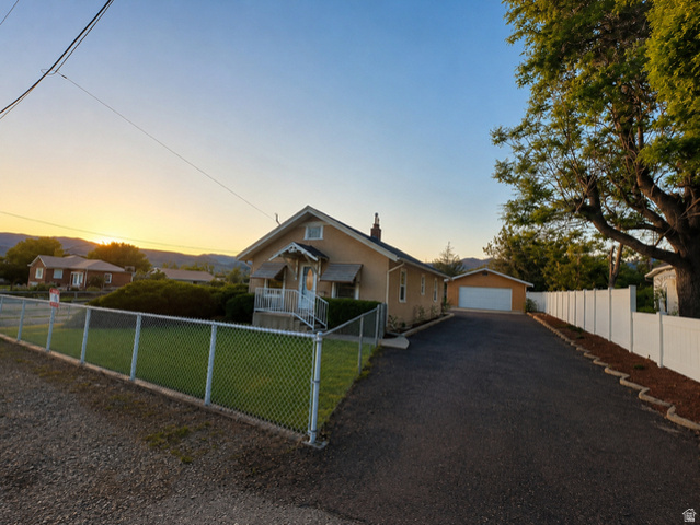 1766 Kenilworth Road Spring Glen, UT 84526 - Photo 2 of 24 Single-story residence featuring a traditional exterior, an attached front porch with white railing, and a detached garage with a white overhead door