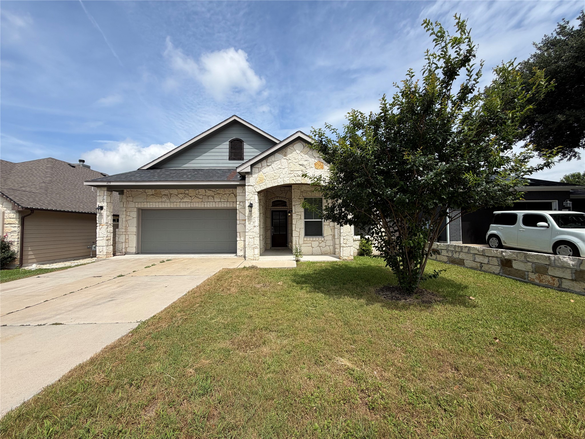 A welcoming facade with stone accents and an attached garage provides inviting curb appeal.