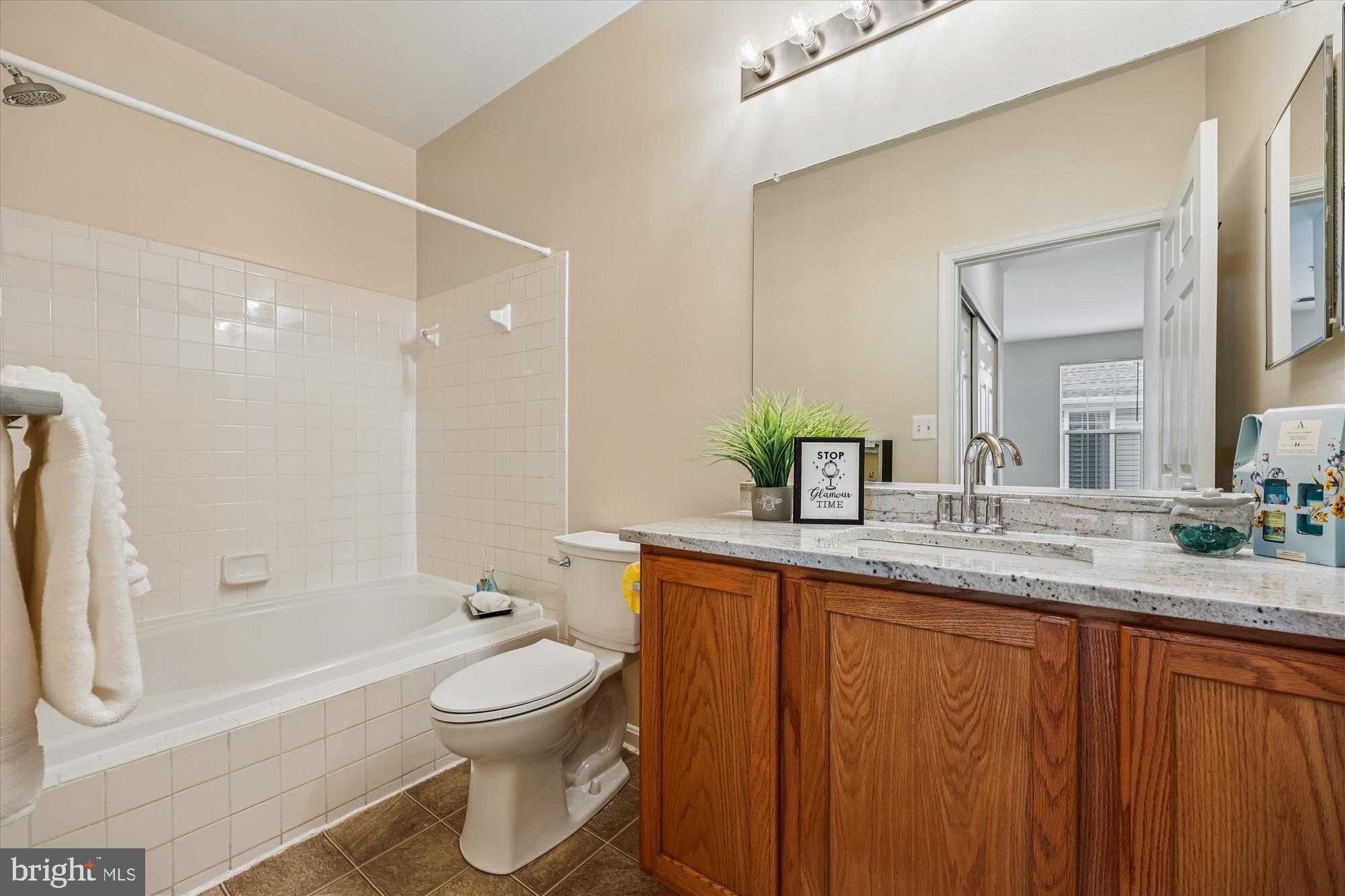 12701 Found Stone Road, Unit 201 Germantown, MD 20876 - Photo 17 of 41 a bathroom with a granite countertop sink toilet a large mirror a bathtub and shower