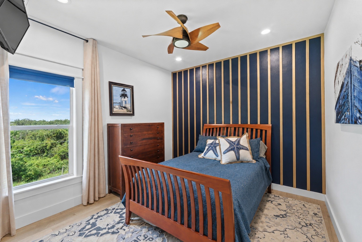 29 Rabbit Drive Port O'Connor, TX 77982 - Photo 9 of 21 Virtually Cleaned: Highlighting custom design details, this bedroom pairs a navy and wood slat accent wall with warm wood furnishings and starfish-themed bedding accents.