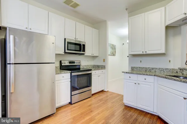 a kitchen with granite countertop a refrigerator stove and microwave