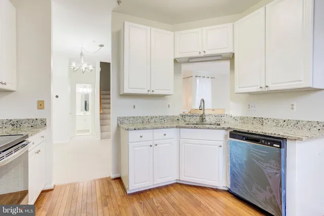 a kitchen with granite countertop cabinets stainless steel appliances and a wooden floor
