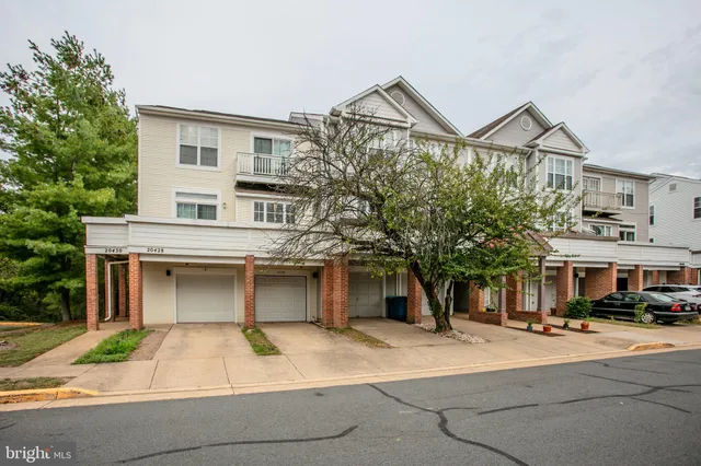 a front view of a building with lots of cars and trees
