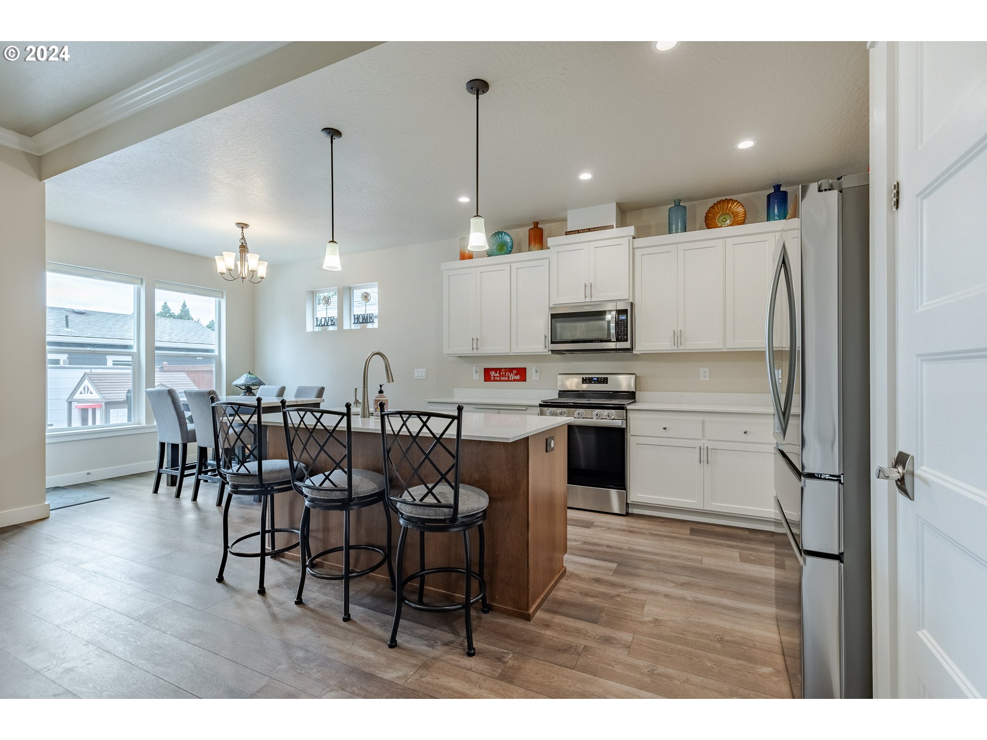 1044 West Olympic Street Springfield, OR 97477 - Photo 10 of 37 a kitchen with kitchen island granite countertop a refrigerator a stove a dining table and chairs with wooden floor