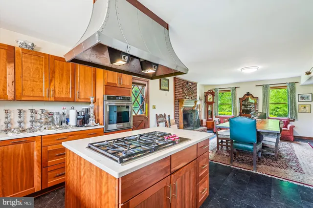 a kitchen with a stove a sink dishwasher and a dining table with garden view