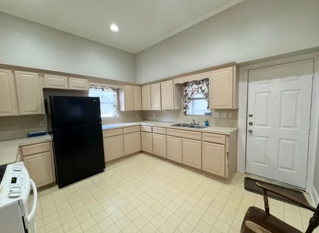 a kitchen with a refrigerator and white cabinets
