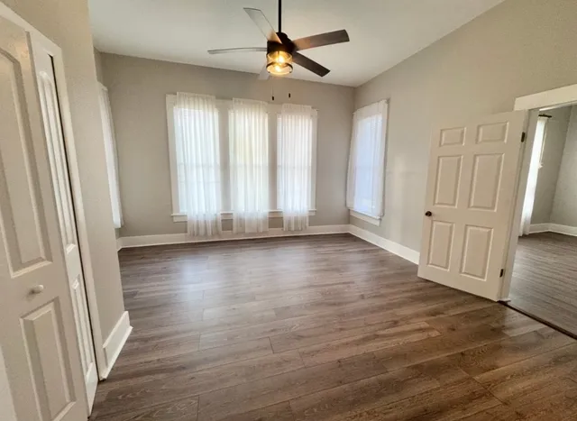 an empty room with wooden floor and windows