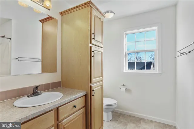 a bathroom with a granite countertop sink toilet a mirror and shower