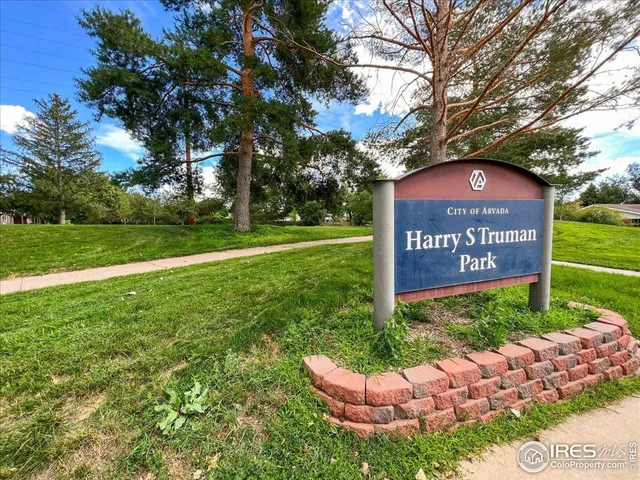 a view of a park that has a sign board large trees