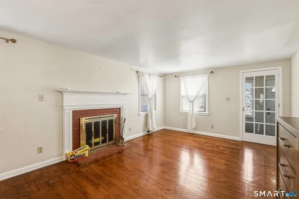 an empty room with wooden floor fireplace and windows