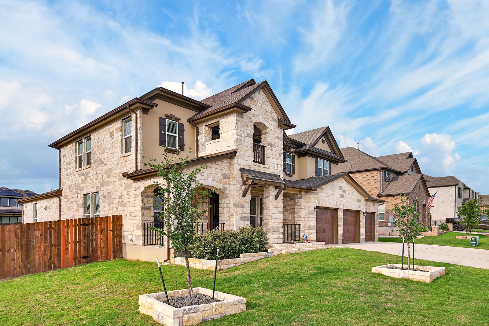 4600 Ercolano Lane Round Rock, TX 78665 - Photo 3 of 37 Two-story stone and stucco exterior featuring a two-car garage with wood-finish doors, a covered entry porch, and a fenced side yard