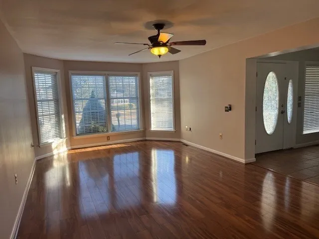 a view of an empty room with wooden floor and a window