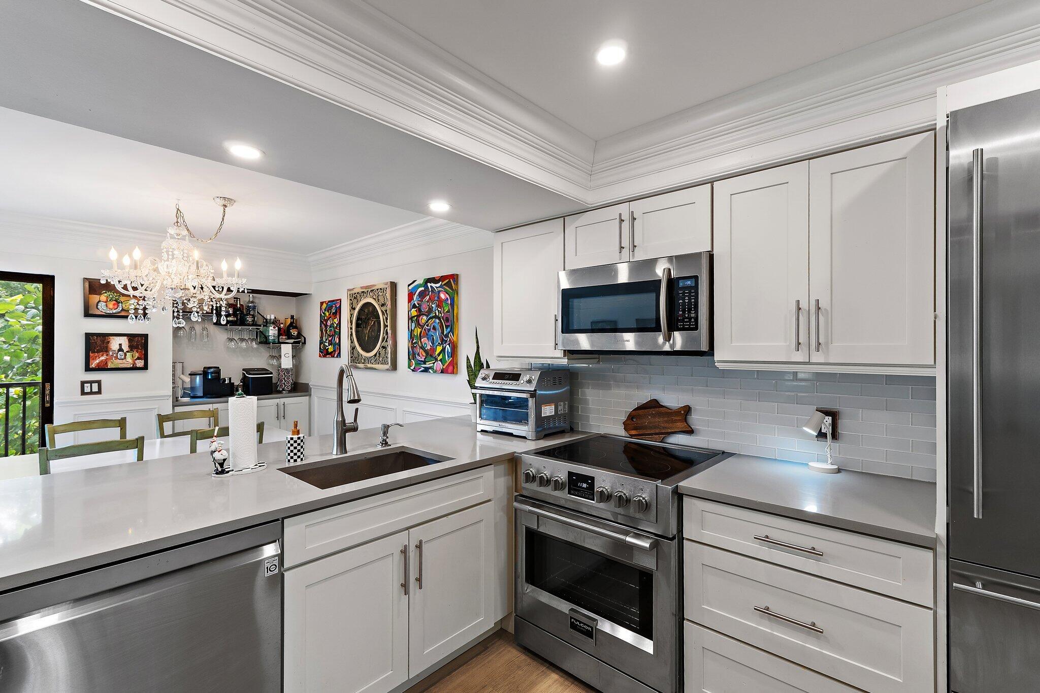 1605 Highway 1, Unit F202 Jupiter, FL 33477 - Photo 7 of 33 a kitchen with stainless steel appliances granite countertop a sink a stove a microwave a refrigerator and cabinets