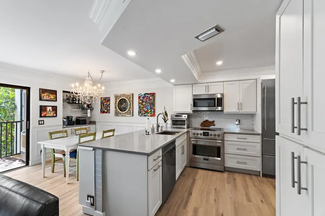 a kitchen with stainless steel appliances granite countertop a stove top oven a sink a dining table and chairs