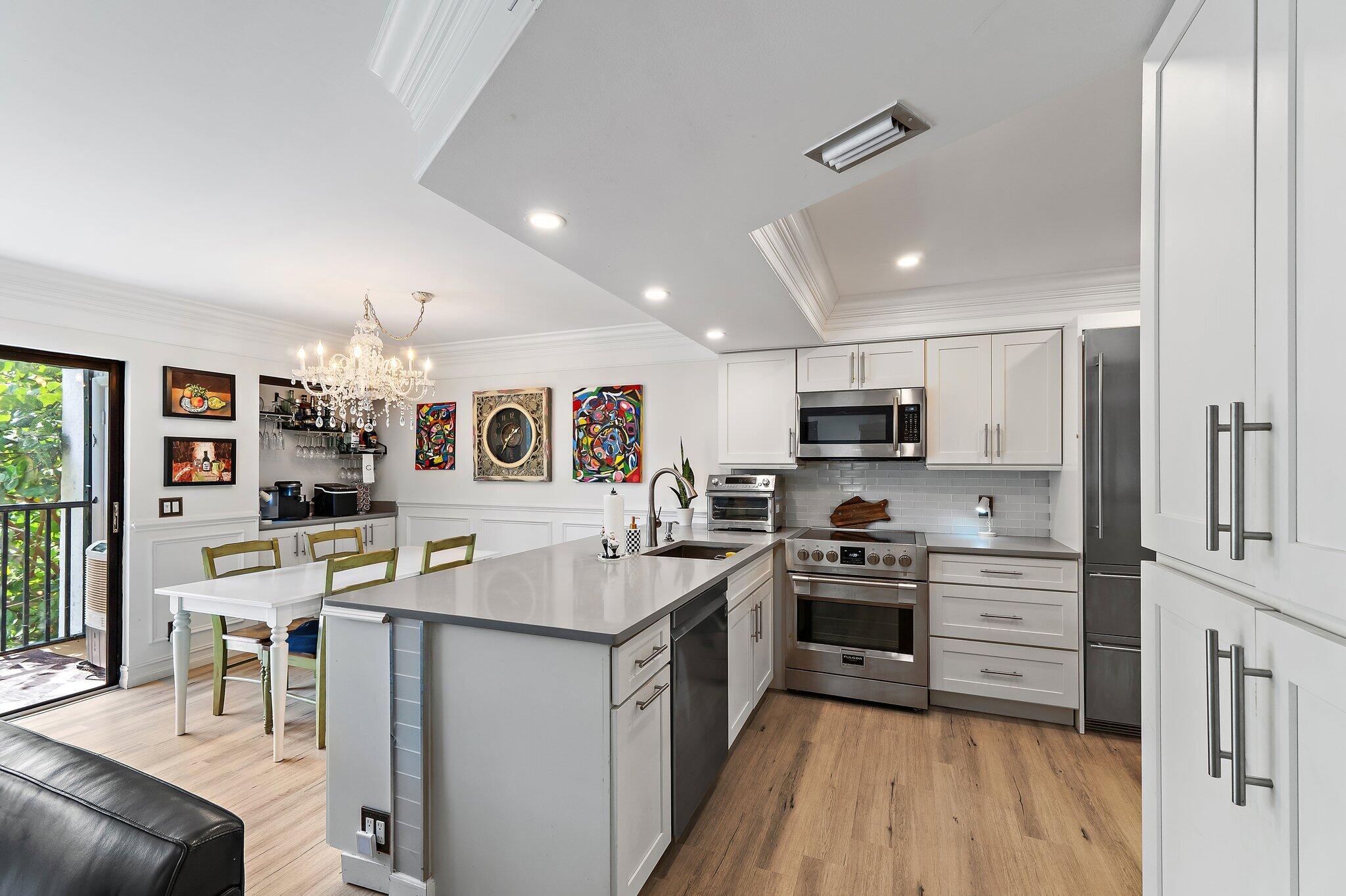 1605 Highway 1, Unit F202 Jupiter, FL 33477 - Photo 10 of 33 a kitchen with stainless steel appliances granite countertop a stove top oven a sink a dining table and chairs