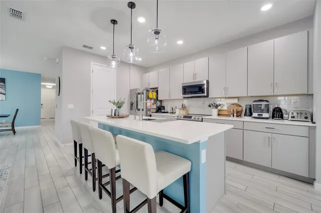 a kitchen with kitchen island granite countertop a dining table chairs and white cabinets