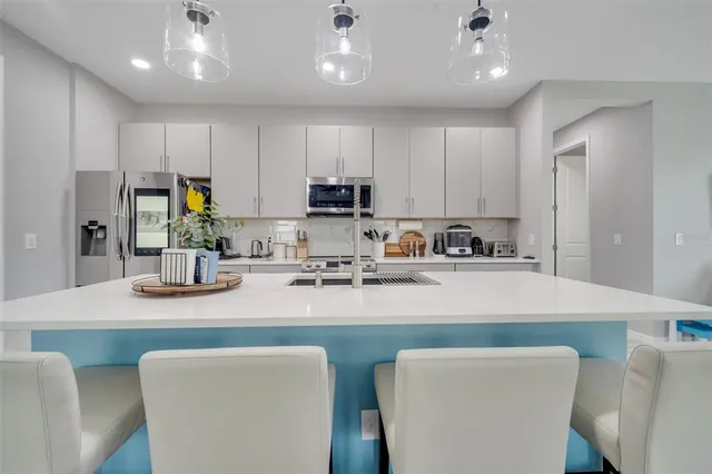 a kitchen with stainless steel appliances granite countertop a sink a stove a refrigerator cabinets and chairs