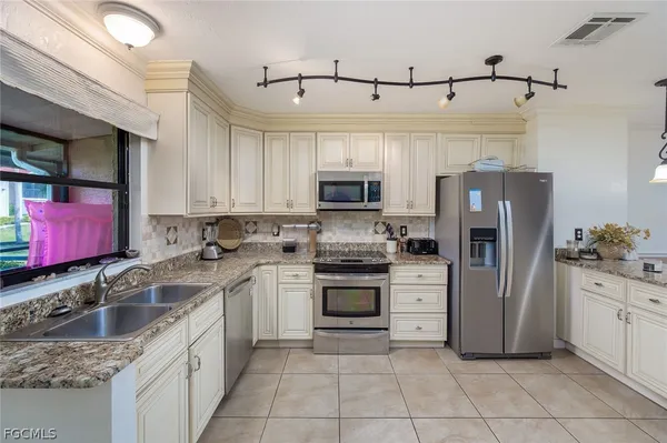 a kitchen with stainless steel appliances granite countertop a sink dishwasher stove top oven and refrigerator