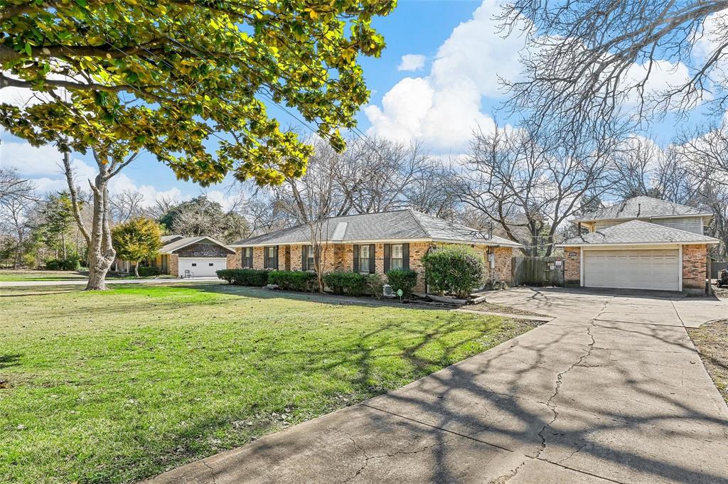 412 West Spinner Road DeSoto, TX 75115 - Photo 2 of 13 Brick exterior with dark shutters, a large front lawn, mature trees, and an attached two-car garage