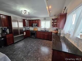 12-14 West 5th Road Queens, NY 11693 - Photo 34 of 43 Kitchen with glass insert cabinets, dark brown cabinets, stainless steel appliances, tasteful backsplash, and dark stone counters