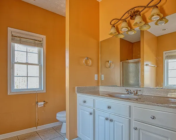 a bathroom with a granite countertop sink mirror vanity and toilet