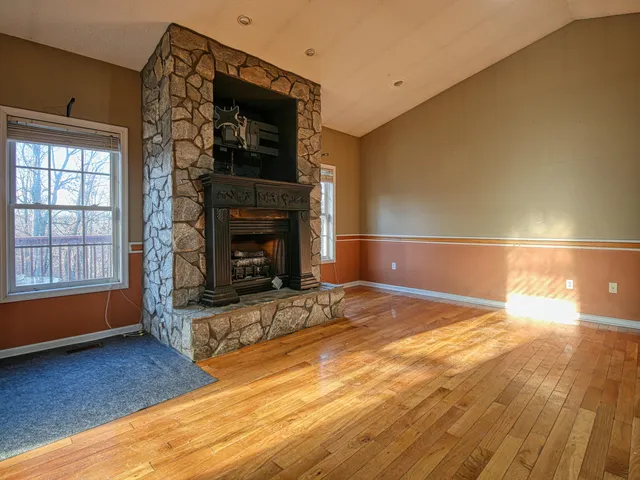a view of empty room with wooden floor and fireplace