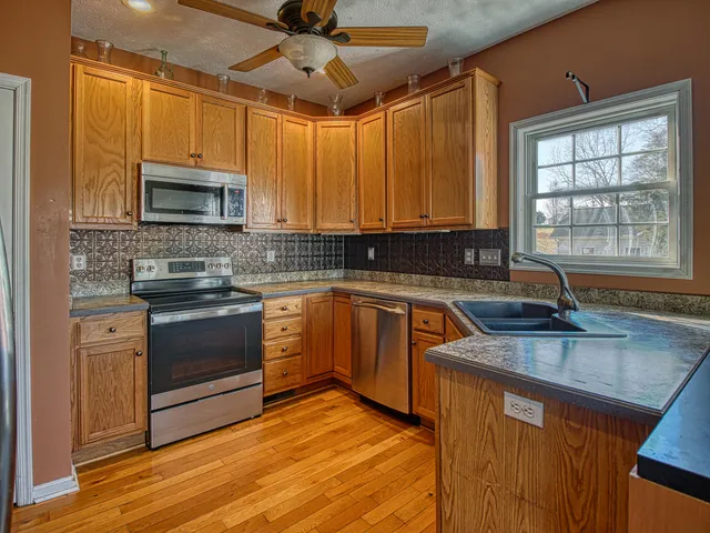 a kitchen with stainless steel appliances granite countertop a sink a stove microwave and cabinets