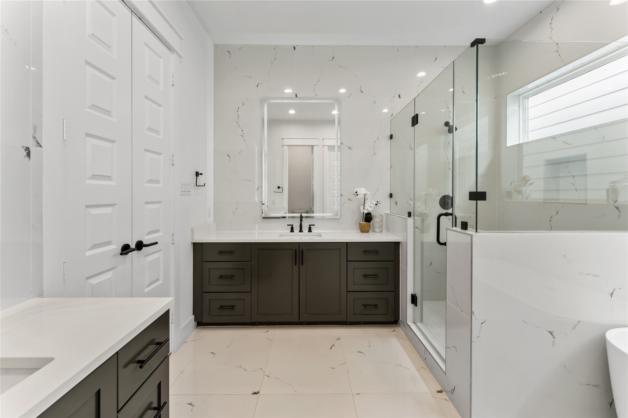 820 East 24th Street Houston, TX 77009 - Photo 21 of 34 A sophisticated dual vanity with custom cabinetry and quartz countertops offers both style and functionality. The expansive walk-in shower with frameless glass and designer finishes creates a clean, modern aesthetic. Bright, reflective surfaces enhance the natural light and elevate the entire space.