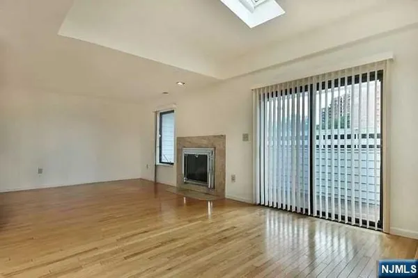 an empty room with wooden floor fireplace and windows