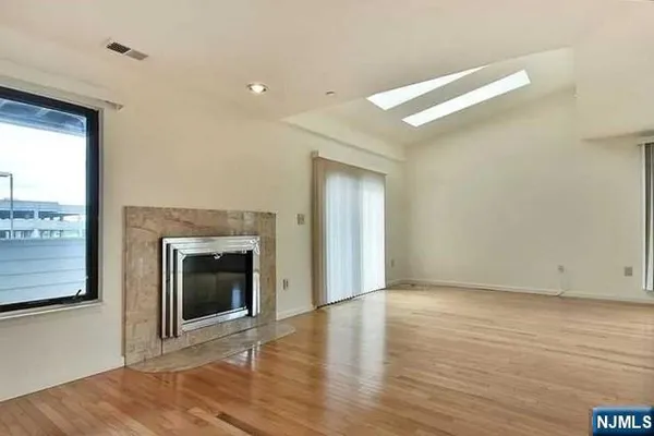 a view of an empty room with wooden floor fireplace and a window