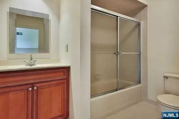 a bathroom with a shower sink vanity mirror and toilet